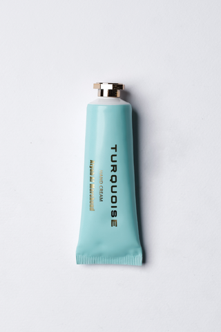A tube of Turquoise hand cream against a white background by Atyab Al Marshoud.